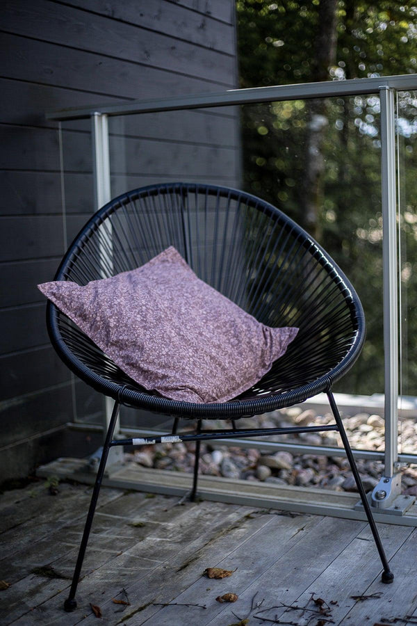 Housse de coussin Floralie écoresponsable, enfilé sur un coussin et déposé sur une chaise à l'extérieur. / Eco-responsible Floral cushion cover, put on a cushion and placed on a chair outside.